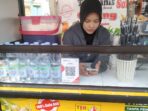 della-es-teh-poci-taman-elektrik-al-azhom-sorot24.jpg` Della pedagang Es Teh Poci tersenyum di gerobak kuning Taman Elektrik Masjid Raya Al-Azhom Tangerang
