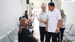 Bupati Maesyal berdiri berbincang dengan ibu-ibu pasien di kursi tunggu Puskesmas