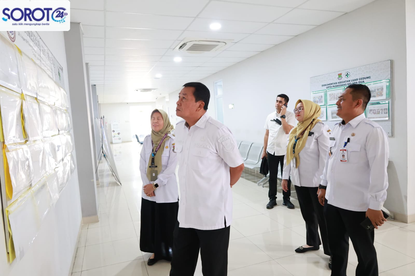 Bupati Maesyal bersama jajaran Puskesmas Kelapa Dua melihat papan informasi di lorong puskesmas