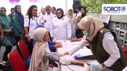 Wabup Intan memakai baju putih melihat petugas cek tekanan darah warga di meja CKG