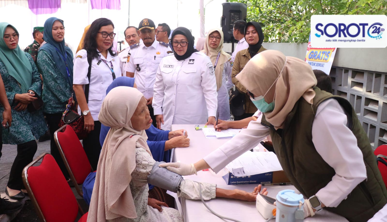 Wabup Intan memakai baju putih melihat petugas cek tekanan darah warga di meja CKG